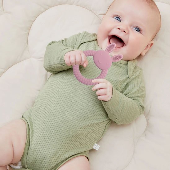 bébé souriant regardant anneau de dentition silicone